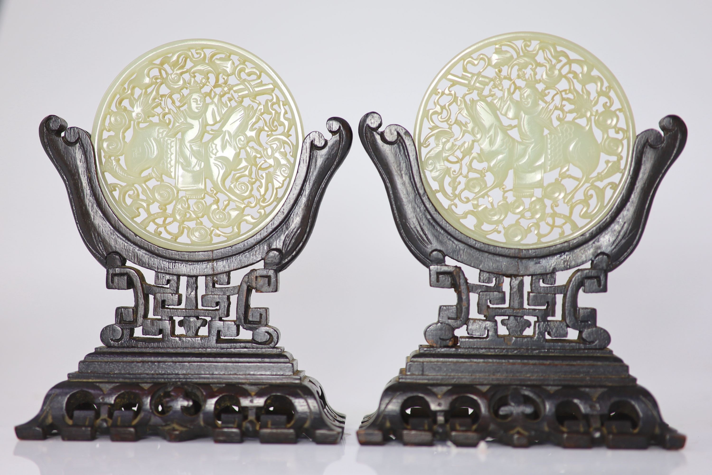 A pair of Chinese pale celadon jade circular plaques, late 19th century, 8.5cm, wood stands